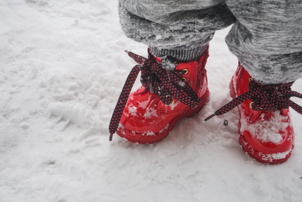 les pieds d'un enfant en chaussures rouges dans la neige